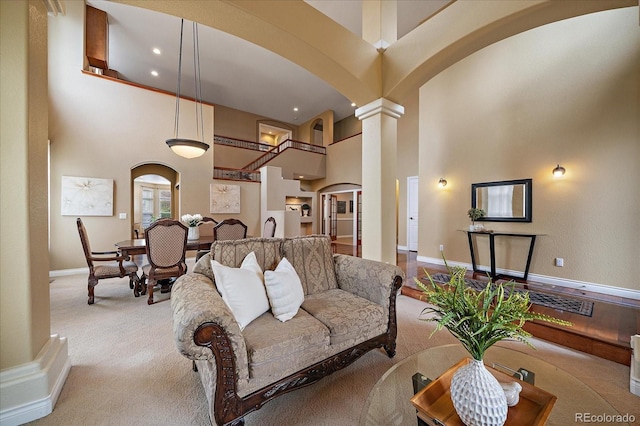 15258 W 75th Pl, Arvada, CO 80007 - living area with arched walkways, a high ceiling, decorative columns, baseboards, and carpet flooring