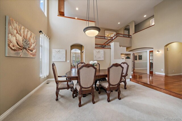15258 W 75th Pl, Arvada, CO 80007 - dining room featuring arched walkways, a high ceiling, light carpet, baseboards, and recessed lighting