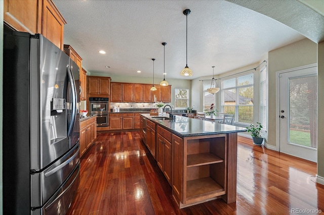 15258 W 75th Pl, Arvada, CO 80007 - kitchen featuring appliances with stainless steel finishes, brown cabinets, dark wood-style floors, a sink, and a textured ceiling