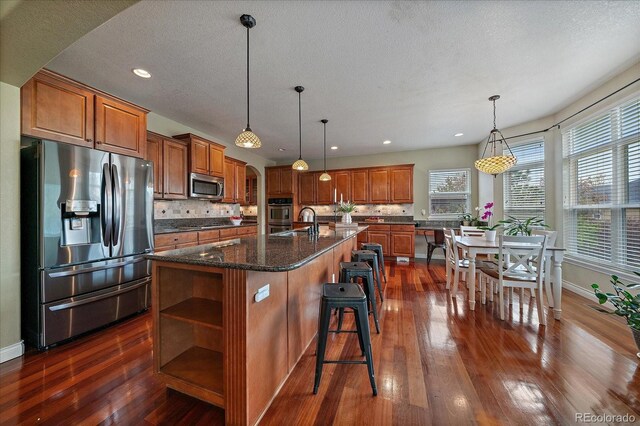 15258 W 75th Pl, Arvada, CO 80007 - kitchen with appliances with stainless steel finishes, brown cabinetry, open shelves, dark wood-style floors, and recessed lighting
