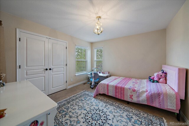 15258 W 75th Pl, Arvada, CO 80007 - bedroom featuring light carpet, baseboards, a chandelier, and a closet