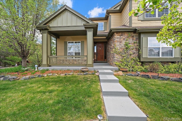15258 W 75th Pl, Arvada, CO 80007 - view of front facade with a porch, a front lawn, stone siding, and board and batten siding
