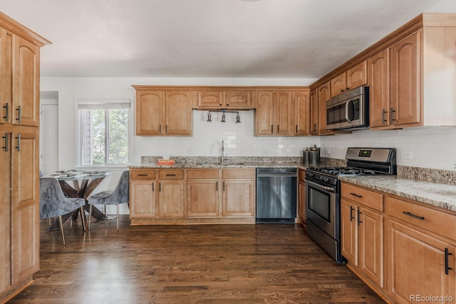 2260 Lilly Dr, Thornton, CO 80229 - kitchen featuring appliances with stainless steel finishes, light stone countertops, dark wood-type flooring, and decorative backsplash