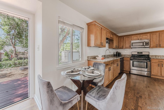2260 Lilly Dr, Thornton, CO 80229 - kitchen with stainless steel appliances, backsplash, dark wood-style flooring, and light stone counters