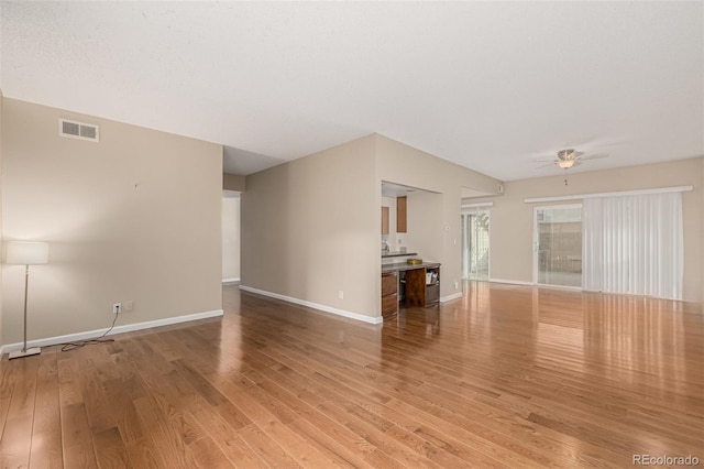 unfurnished living room featuring a ceiling fan, light wood-style flooring, visible vents, and baseboards