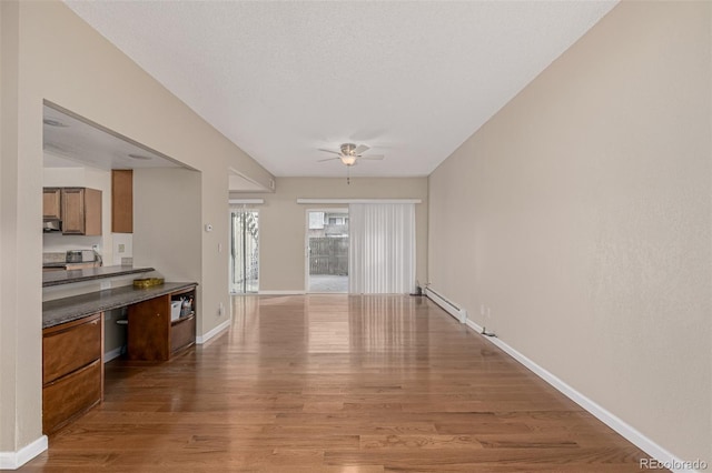 interior space featuring a baseboard radiator, wood finished floors, a ceiling fan, and baseboards