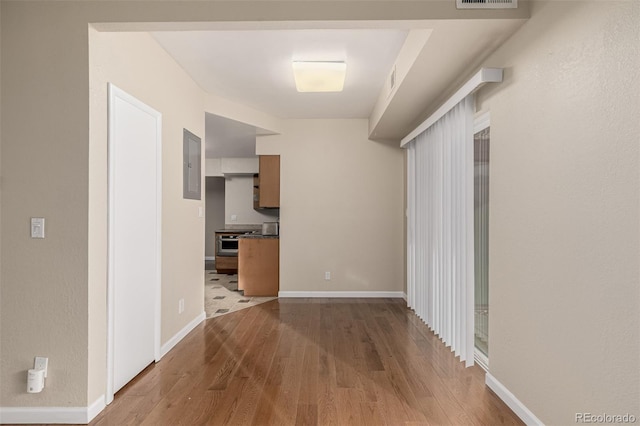 corridor with visible vents, electric panel, baseboards, and wood finished floors