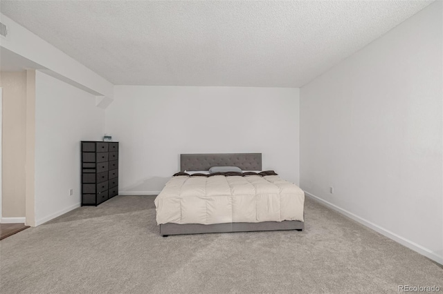 bedroom with visible vents, a textured ceiling, baseboards, and carpet flooring