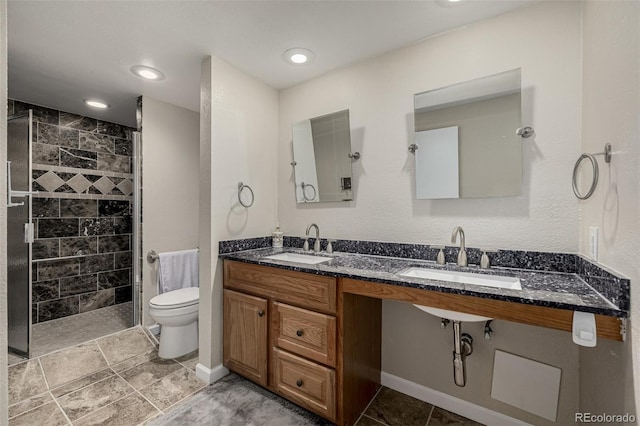 bathroom with toilet, baseboards, a tile shower, and a sink