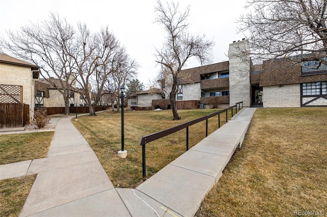 view of property's community with a residential view, fence, and a lawn