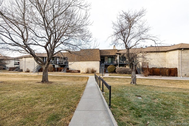 single story home with a chimney, stucco siding, stairway, a front yard, and fence