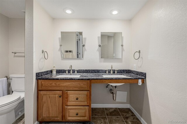 7250 Eastmoor Dr Unit 105, Denver, CO 80237 - bathroom featuring toilet, double vanity, baseboards, and tile patterned floors
