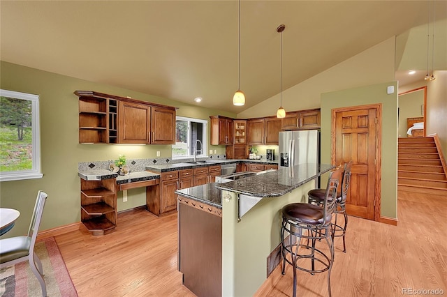 28065 Camel Heights Cir, Evergreen, CO 80439 - kitchen with stainless steel appliances, open shelves, brown cabinets, light wood finished floors, and vaulted ceiling