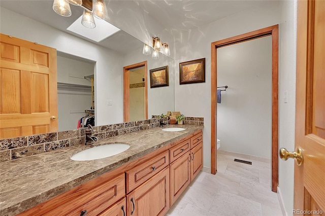 28065 Camel Heights Cir, Evergreen, CO 80439 - bathroom featuring double vanity, toilet, a walk in closet, and baseboards
