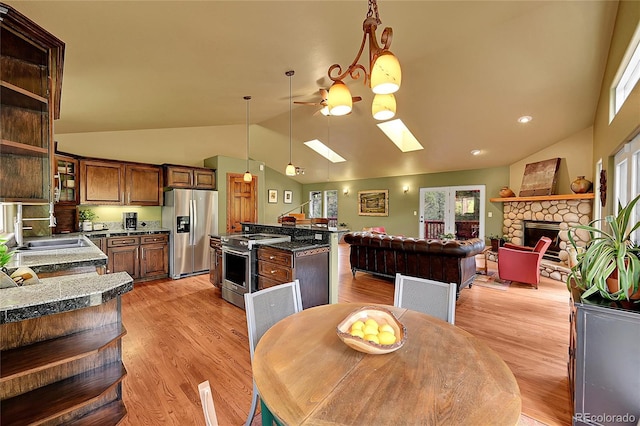 28065 Camel Heights Cir, Evergreen, CO 80439 - dining area featuring vaulted ceiling, a stone fireplace, ceiling fan, a skylight, and light wood finished floors