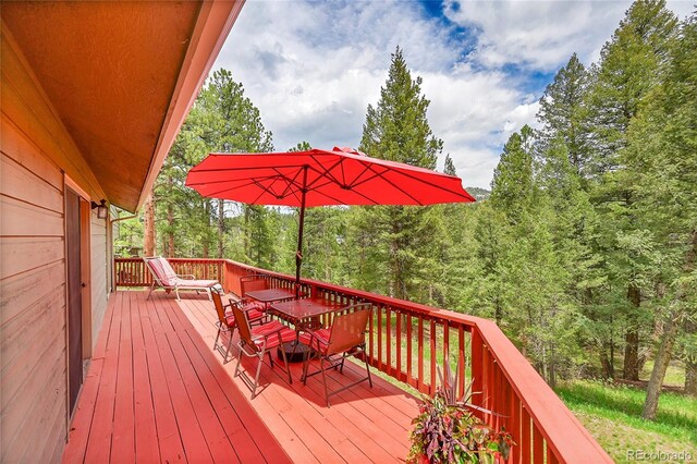 28065 Camel Heights Cir, Evergreen, CO 80439 - wooden terrace with outdoor dining area and a forest view