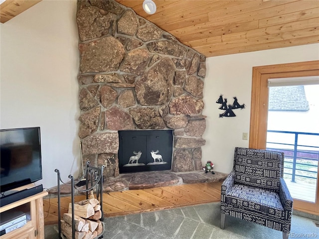 sitting room featuring vaulted ceiling, a stone fireplace, and wooden ceiling