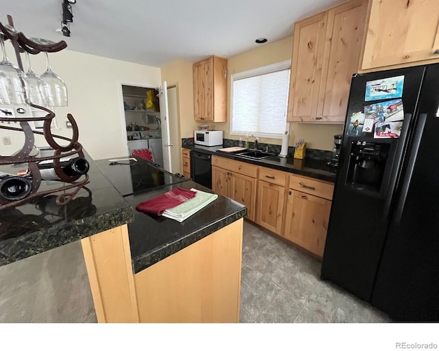 kitchen with light brown cabinetry, sink, separate washer and dryer, hanging light fixtures, and black appliances