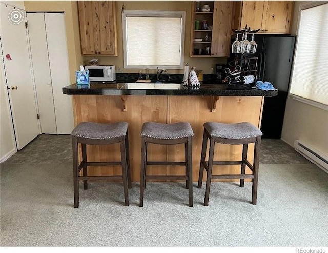 kitchen with light colored carpet, a wealth of natural light, and a kitchen breakfast bar