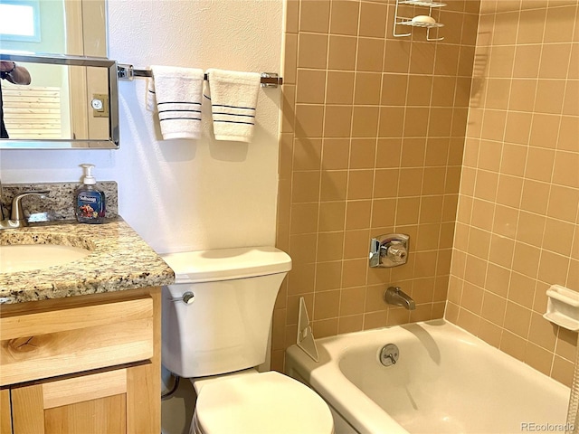 full bathroom featuring vanity, tiled shower / bath, and toilet