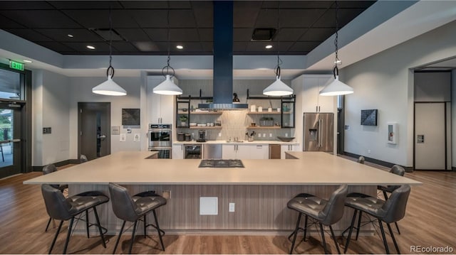 kitchen featuring stainless steel appliances, hanging light fixtures, a spacious island, and a breakfast bar area