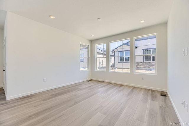 spare room with light wood-type flooring and plenty of natural light