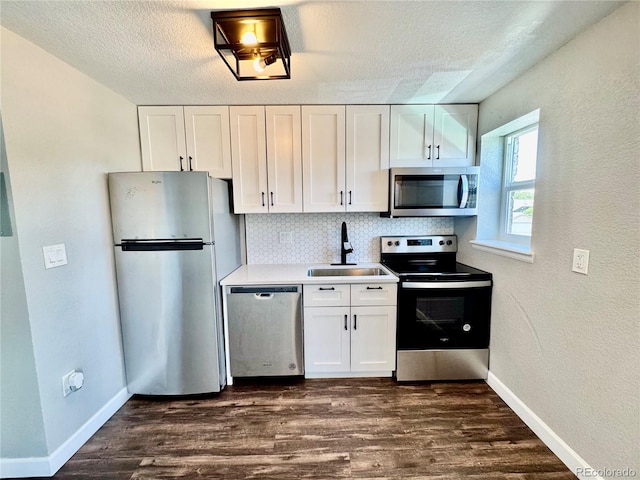 1285 Colorado Blvd Unit 3, Denver, CO 80206 - kitchen featuring appliances with stainless steel finishes, backsplash, white cabinetry, dark wood-style flooring, and a textured ceiling