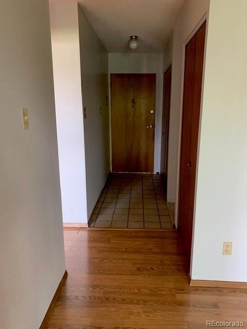 corridor with light wood finished floors and baseboards