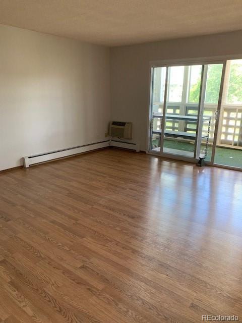 spare room featuring wood finished floors, plenty of natural light, and a wall mounted air conditioner