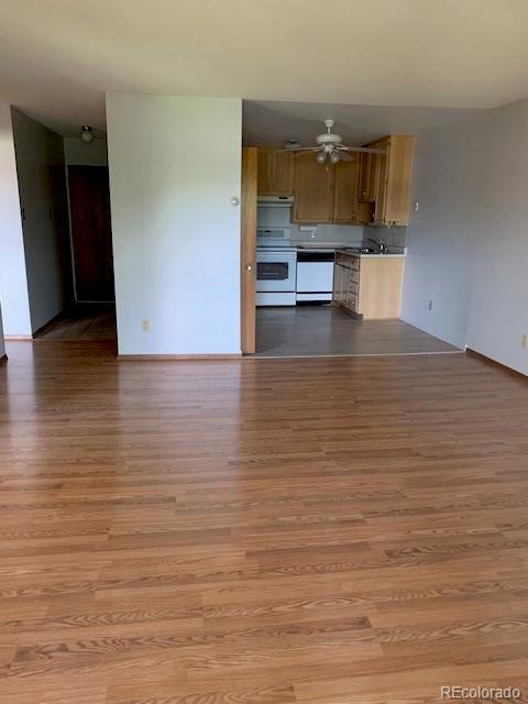 unfurnished living room featuring wood finished floors, a ceiling fan, and baseboards