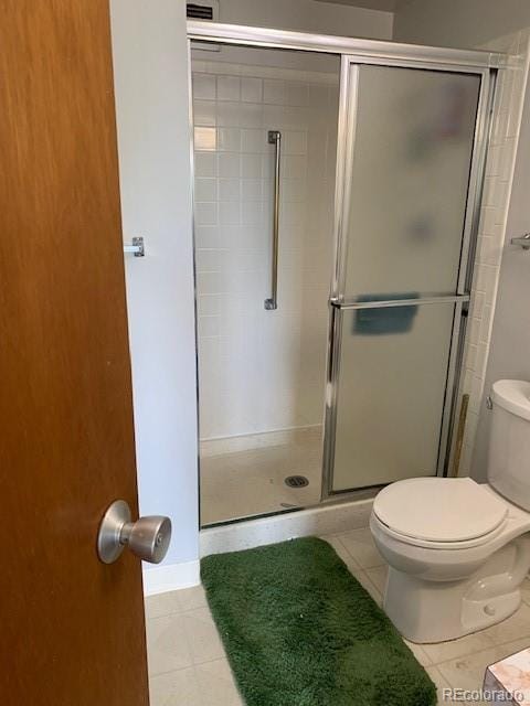 full bath featuring tile patterned flooring, toilet, and a shower stall
