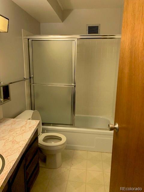 bathroom featuring vanity, combined bath / shower with glass door, and toilet