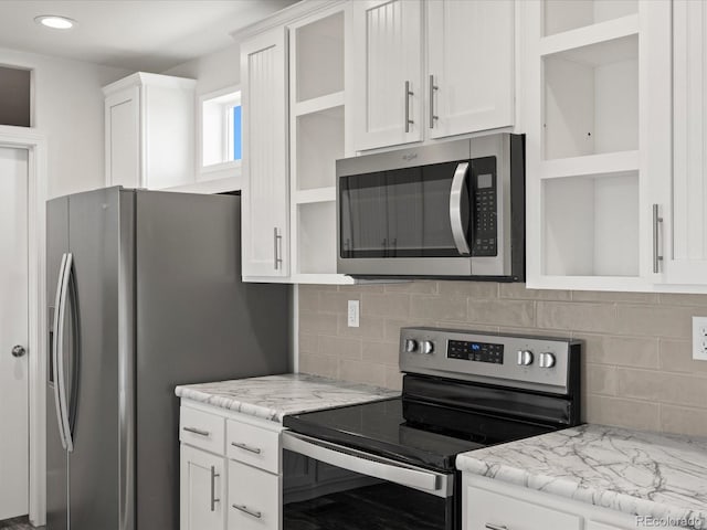 kitchen with stainless steel appliances, light stone counters, white cabinetry, and tasteful backsplash