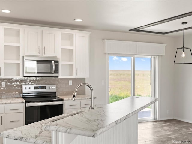 kitchen with decorative light fixtures, light stone counters, light hardwood / wood-style flooring, stainless steel appliances, and tasteful backsplash