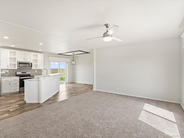 kitchen with white cabinetry, hardwood / wood-style floors, a center island with sink, and stainless steel appliances