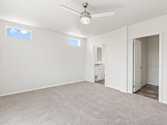 unfurnished bedroom with dark colored carpet, ceiling fan, and ensuite bath