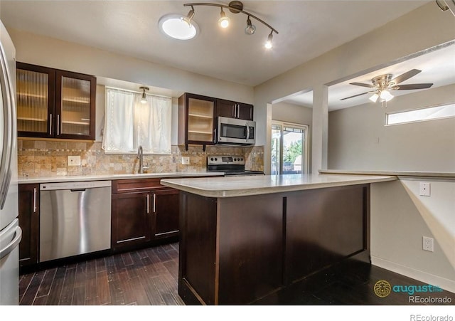 kitchen with glass insert cabinets, tasteful backsplash, a sink, light countertops, and stainless steel appliances