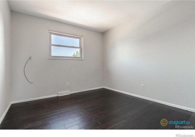 empty room with visible vents, baseboards, and dark wood finished floors
