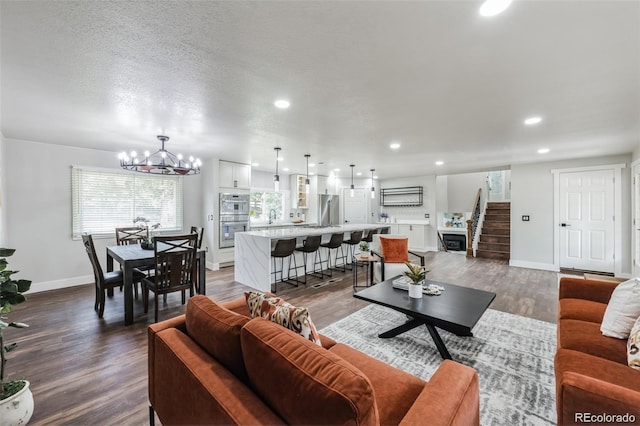 living room featuring a textured ceiling, sink, a chandelier, and dark hardwood / wood-style floors