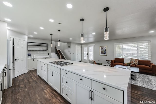 kitchen with appliances with stainless steel finishes, decorative light fixtures, a center island, dark hardwood / wood-style floors, and white cabinetry