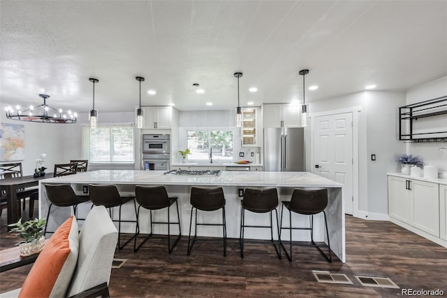 kitchen featuring a spacious island, white cabinetry, pendant lighting, and appliances with stainless steel finishes