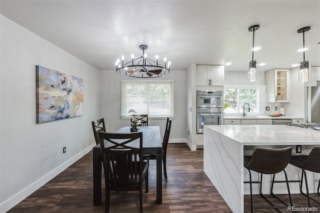 dining space featuring dark wood-type flooring, sink, a chandelier, and plenty of natural light