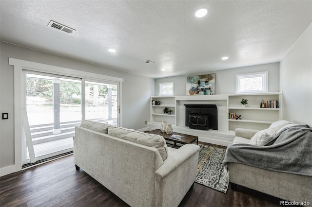 living room with a textured ceiling, a wealth of natural light, and dark wood-type flooring