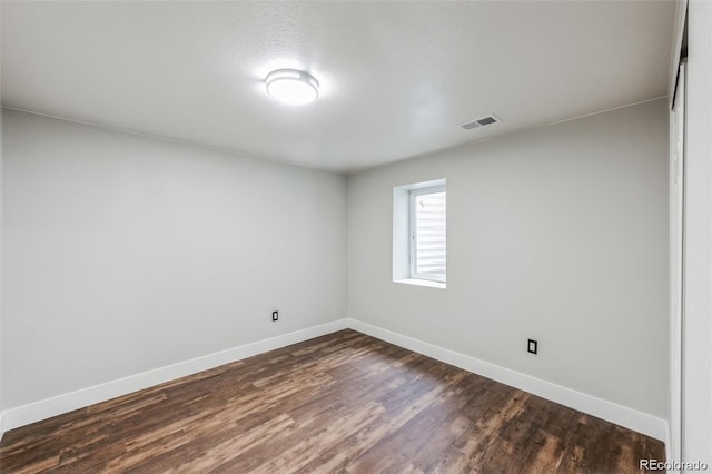 empty room with dark wood-type flooring and a textured ceiling