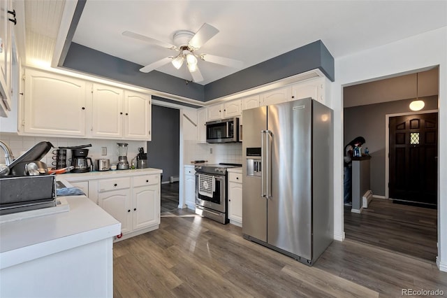 kitchen featuring stainless steel appliances, decorative backsplash, dark hardwood / wood-style flooring, white cabinets, and ceiling fan