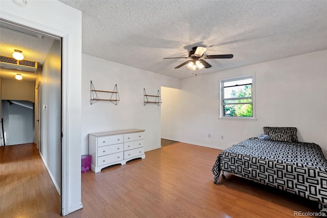 bedroom with hardwood / wood-style floors, a textured ceiling, and ceiling fan