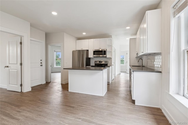 1037 12th St, Boulder, CO 80204 - kitchen featuring stainless steel appliances, decorative backsplash, white cabinetry, a kitchen island, and recessed lighting
