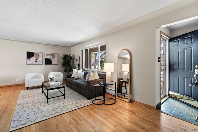 living room with hardwood / wood-style flooring, a baseboard radiator, and a textured ceiling