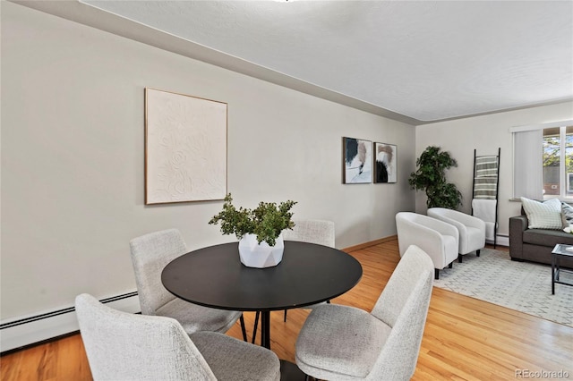 dining room with a baseboard heating unit and wood-type flooring