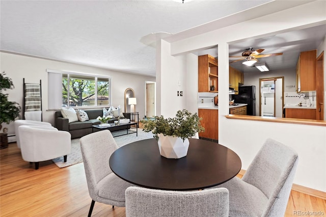 dining room featuring ceiling fan, light hardwood / wood-style flooring, and a baseboard heating unit